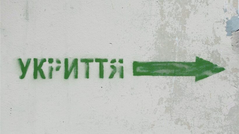 Green spraypainted text "ukrittia" on a white concrete background.